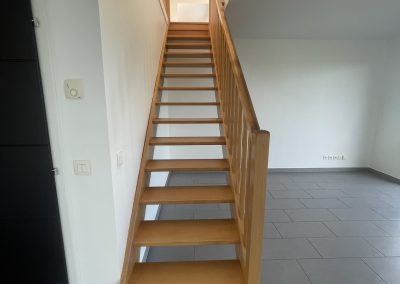 Escalier en bois avec la pièce du bas ayant un carrelage gris. Ce sont des travaux réalisés par MIA.